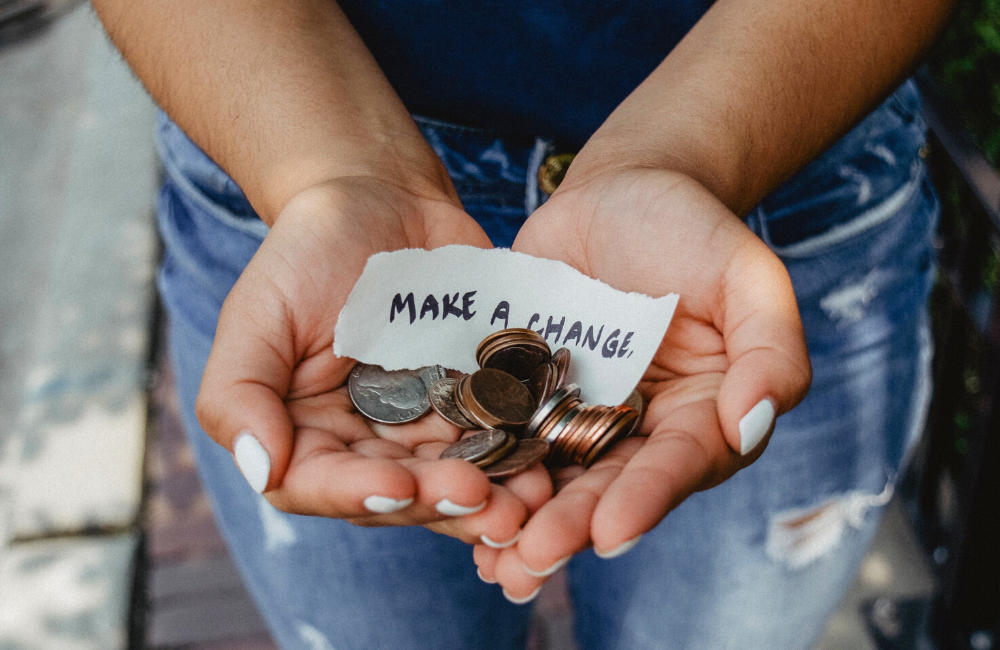 Open palmed hands holding coins and a note reading