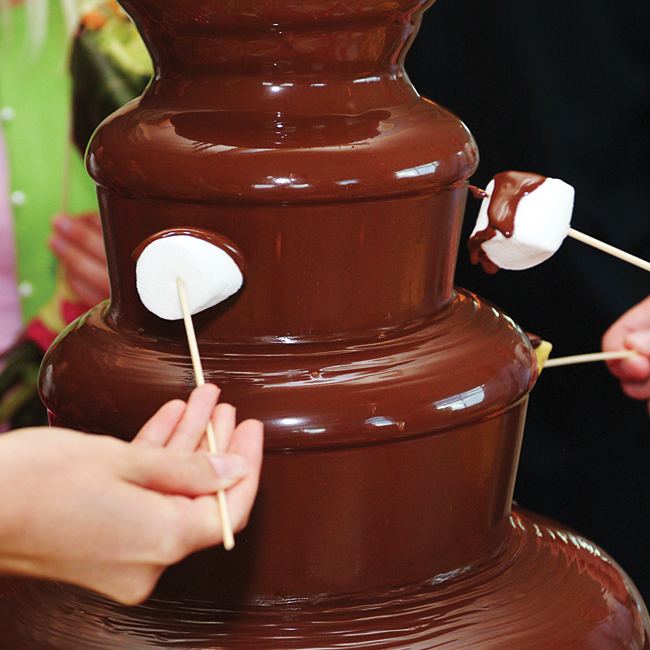 Marshmallows on skewers dipped on a chocolate fountain