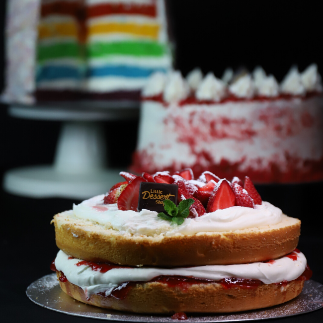 Dessert Victoria sponge cake with white creme and jam in the middle, and frosting and fresh strawberries on top